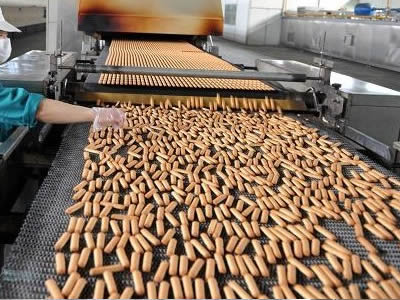 A worker is operating the conveying equipment and several biscuits on the conveyor belt.