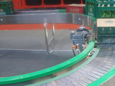 A round conveyor belt machine with several beers on the belt.