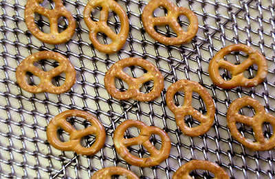 Several baked biscuits on the chain link oven mesh belt.