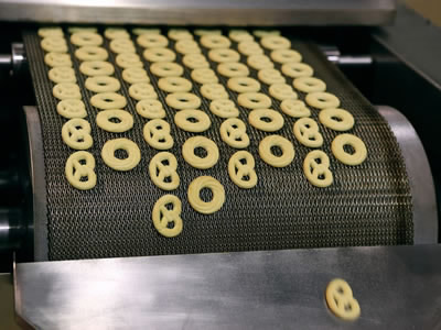 Several baked cookies on the compound weave oven mesh belt slope.