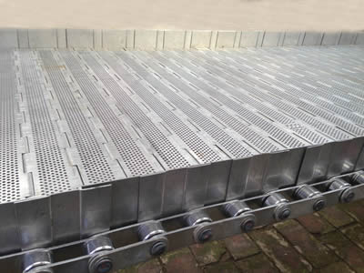 A piece of steel chain plate conveyor belt with perforated chain plate and dog leg side plates on the ground.