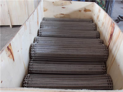 Several rolls of stainless steel balanced weave belts in the wooden case.